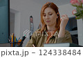 Woman engages in remote work while taking notes and talking on the phone 124338484