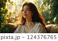 Smiling Woman in White Lace Top Sitting on Beige Couch in Sunlit Room 124376765