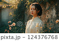 Young Woman in Beige Blouse Contemplating in a Sunlit Garden 124376768