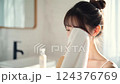 Young Woman Drying Face with White Towel in Bright Bathroom 124376769