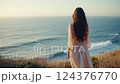 Woman in Pink Dress Overlooking Ocean at Sunset 124376770