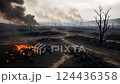 A desolate landscape with burnt trees and active fires, creating a scene of destruction and environmental devastation. The image represents the aftermath of a catastrophic event. 124436358