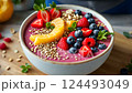 Preparing a vibrant breakfast bowl with fresh berries and sliced oranges in a rustic setting 124493049