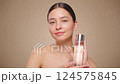 Smiling woman holds bottle with cosmetic tonic. Video of attractive woman with perfect makeup on beige background. Beauty and skin care concept. Removing makeup. Slow motion 124575845