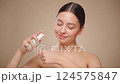 Portrait young woman uses creams of her face. Concept for fresh moisturized skin beautiful closeup cosmetic face happy healthy model.   Model with a bottle of face cream. Slow motion 124575847