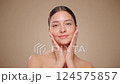 Beautiful Young Woman Touches Her Perfect Face. Natural Cosmetic Skincare Products. Woman demonstrate moisturizing facial care. Elevating Close-up Portrait with Isolated Background. Slow motion 124575857