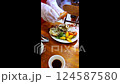 A waiter uses his hands and tongs to cut up a crab for customers at a restaurant in Nha Trang, Vietnam. The whole baked crab is served with a carrot flower and greens. Vertical video, slow motion. 124587580