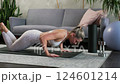 Young beautiful blonde doing knee push-ups on yoga mat in cozy living room. Gray sofa and 124601214