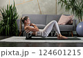 Young blonde woman doing physical exercises lying on her back on a fitness roller on a yoga mat in 124601215