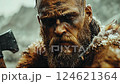 Intense warrior portrait in snowy landscape with axe held firmly during dramatic battle preparation 124621364