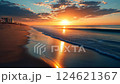 Beautiful summer sunset on a tranquil beach with gentle waves and vibrant colors reflecting on the water 124621367