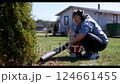 Woman using leaf blower to tidy yard in bright springtime setting near cozy home 124661455