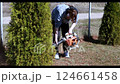 Man uses leaf blower to clear yard near bushes on a sunny day 124661458