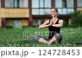Yoga expert meditating in lotus pose on grassy park mat, practicing mindful breathing during serene golden hour sunlight with calm, relaxed posture 124728453