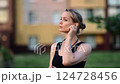 Professional runner setting wireless earphones, showing intense concentration while preparing for nighttime exercise in urban park landscape 124728456