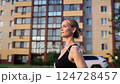 Active female runner navigating suburban street, maintaining strong rhythm with determined stride during golden-hour fitness session 124728457