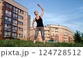 Fitness enthusiast performing side bends near residential buildings, demonstrating core strength and wellness in urban outdoor environment 124728512