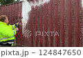 Cleaner in work clothes applies a cleaning agent to the surface of a shipping container. 124847650