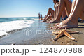 People with barefoot feet on the seaside sunbathing on beach near sea wave 124870988