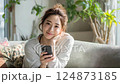 自宅のリビングでスマホを見ている若い女性 124873185