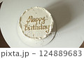 Top view of festive style white cream cake decorated with gold drops and happy birthday inscription on round white table. Homemade delicious luxury vanilla dessert for birthday party. Camera moving 124889683