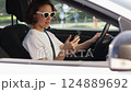 female driver uses smartphone for surfing internet social media inside car on parking. Woman checks work email chats, reads news on cellphone. Modern lifestyle concept. 124889692