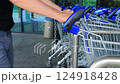 Close-up Male Hand Shopper Pulling Shopping Cart from Row in Supermarket or Grocery Store. Take a Grocery Cart for Shopping. 124918428
