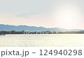 Morning atmosphere of a fishing village with fishing boats passing by on the sea floor. Seaside village background and mountains under the sky with morning rays. 124940298