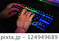 Womens hands type text on an RGB keyboard. Close up of pro cyber sport gamer play with RGB keyboard 124949689