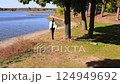 Happy Woman in white jacket walking on the shore of beautiful river in sunny autumn day. Female blonde at lakeside enjoying fall nature landscape. 124949692