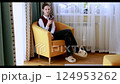 Relaxing at home with a mobile device in a cozy armchair on a sunny afternoon 124953262