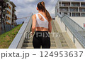 Workout on city street. Slender Caucasian blonde in white top runs up stairs, doing sports, jogging, athlete, healthy lifestyle. Slow motion. 124953637