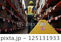 Warehouse workers are pulling carts to move boxes of merchandise to be arranged on shelves in a warehouse. 125131933