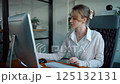young woman is sitting at her desk reading her financial report and comparing the results on her desktop 125132131
