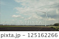 Wind turbines rotating in cultivated field under cloudy sky 125162266