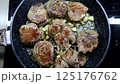 Close-up of seasoned beef medallions browning in a frying pan with diced onions, showing rich texture and appetizing golden crust 125176762