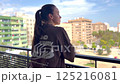 Rear view of a young woman standing on balcony at home 125216081