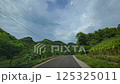 Countryside road surrounded by lush greenery under a bright clear sky on a sunny day. Tranquil and picturesque outdoor scene perfect for nature and travel contexts. 125325011