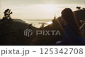 Woman observing sunset over mountain valley landscape 125342708