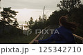 Woman walking on wooden path at sunset near the sea 125342710