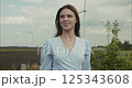 Young woman smiling near wind turbines in agricultural field 125343608