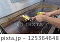 Cook preparing delicious grilled vegetables and chicken meat on a professional kitchen griddle, showcasing culinary skills and craftsmanship. Delicious ingredients and healthy cooking in action. 125364648