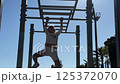 Girl wearing sunglasses exercising on monkey bars 125372070