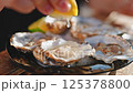 Woman hand pours oysters lemon juice. 125378800