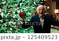 Senior man celebrating his success and winning a pension lottery with cash and dollar bills raining down 125409523