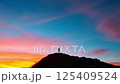 An aerial silhouette of a person ascending a mountain at sunset 125409524