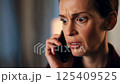 A person receiving bad news on the phone, their expression changing to one of concern or disbelief 125409525
