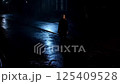 A woman walking alone on a dark, wet street at night 125409528