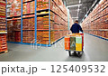 A factory worker pushing a cart filled with candies through a storage room 125409532