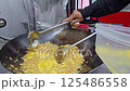 chef actively stirring fried rice in a large wok, showcasing professional cooking techniques and steaming preparation in a kitchen environment. An example of authentic culinary skill and efficiency. 125486558